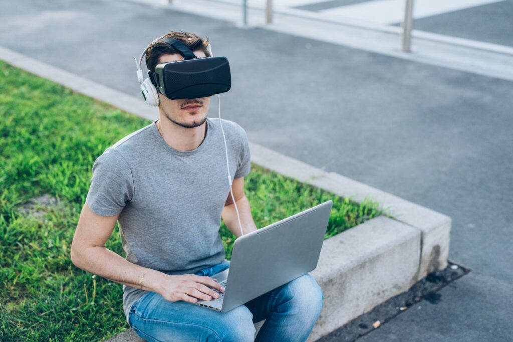 Das Metaverse einfach erklärt: Ein junger Mann mit Laptop und 3D-Brille